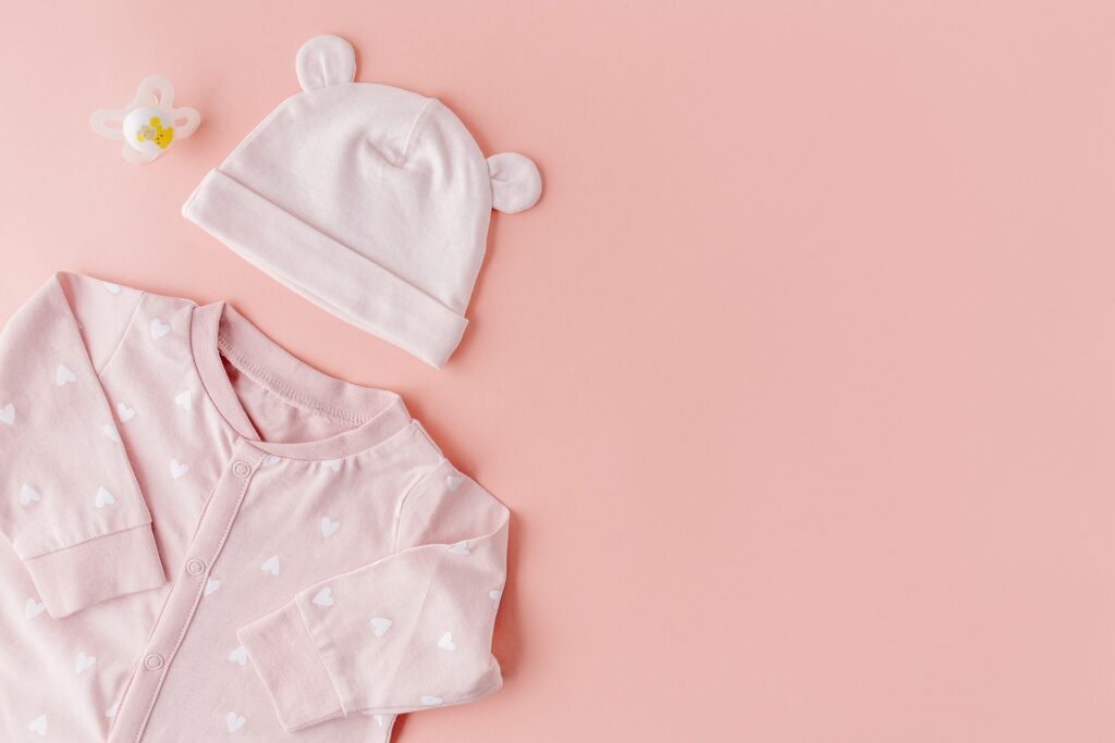 Minimalist baby outfit and dummy on a pink background