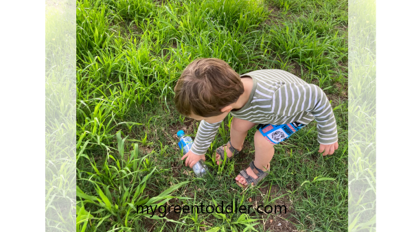 Boy picking up plastic bottle from grass