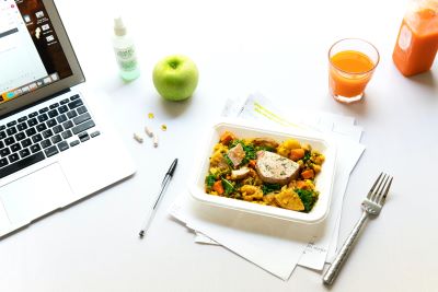 waste free office lunch - laptop, apple, glass and lunch container sitting on top of papers
