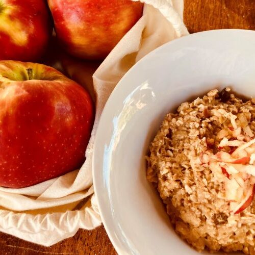 Bowl of apple and cinnamon porridge next to a bag of apples
