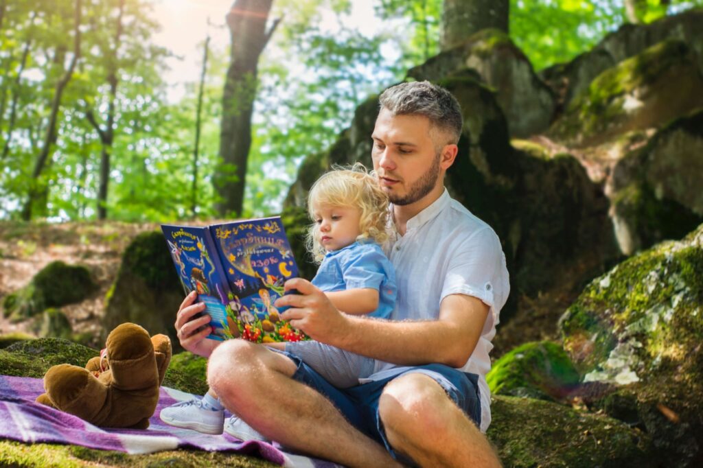 Man reading book to child under a tree