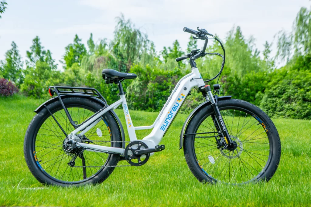 Photo of white electric bike parked on grass with trees in the background